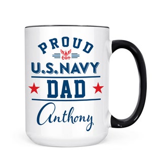 May include: White ceramic coffee mug with a black handle. The mug has a navy blue design that says "Proud U.S. Navy Dad Anthony".