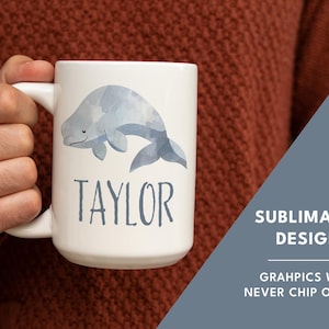 May include: White ceramic mug with a watercolor illustration of a beluga whale and the name "TAYLOR" printed in blue.