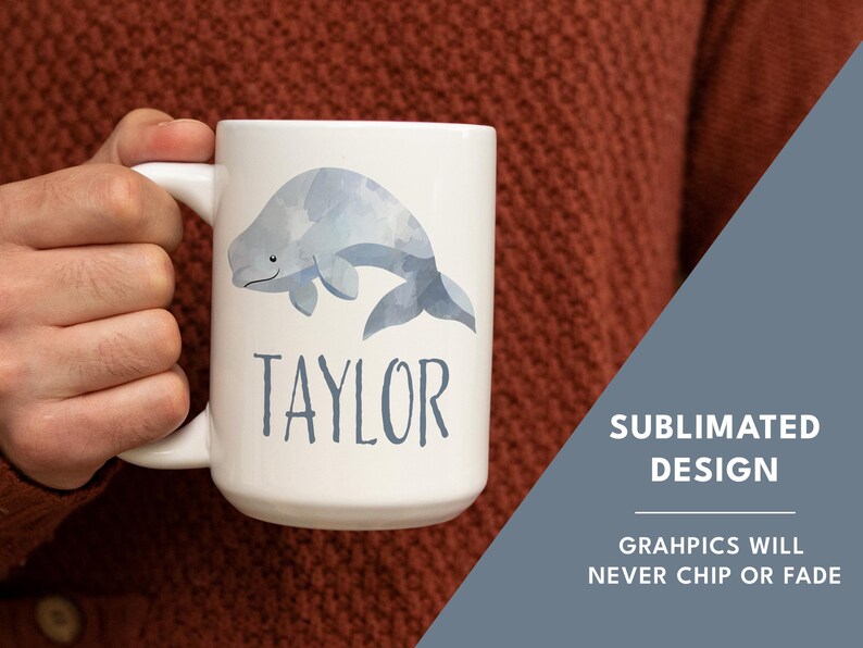May include: White ceramic mug with a watercolor illustration of a beluga whale and the name "TAYLOR" printed in blue.