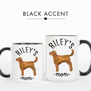 May include: Two white ceramic mugs with black accents. Each mug features a brown dog illustration and the text "Riley's mom." The mugs are different sizes, with the larger mug having a black handle and rim.