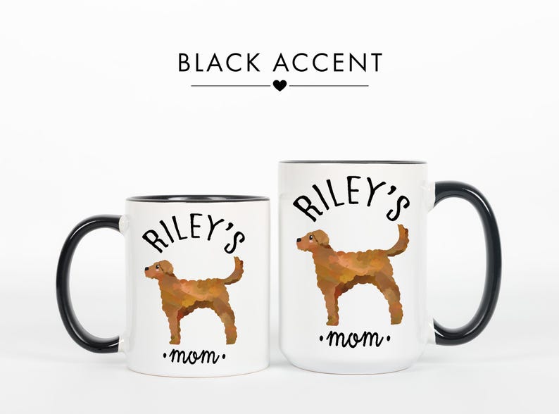 May include: Two white ceramic mugs with black accents. Each mug features a brown dog illustration and the text "Riley's mom." The mugs are different sizes, with the larger mug having a black handle and rim.