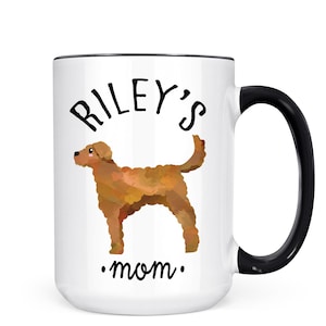 May include: White ceramic mug with a black handle and rim. The mug features the text "Riley's mom" with a watercolor illustration of a brown dog. A perfect gift for dog lovers.