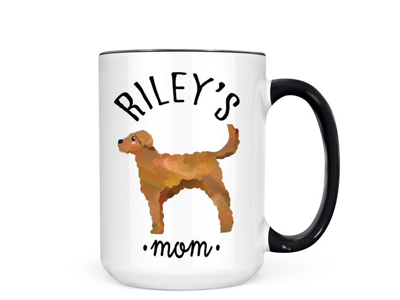May include: White ceramic mug with a black handle and rim. The mug features the text "Riley's mom" with a watercolor illustration of a brown dog. A perfect gift for dog lovers.