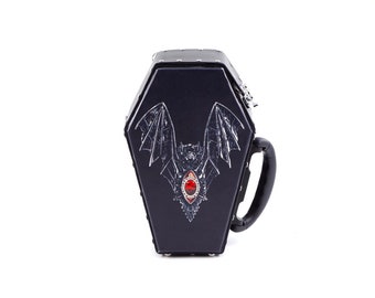 May include: Black coffin-shaped box with a silver handle and a bat with a red jewel design.