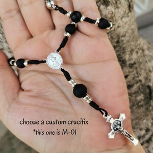 Könnte beinhalten: Schwarze Rosenkranzperlen mit silbernen Akzenten und einem silbernen Kruzifix. Die Perlen sind aus schwarzem Onyx und das Kruzifix ist schlicht gehalten. Der Text "choose a custom crucifix *this one is M-01" ist im Bild sichtbar.