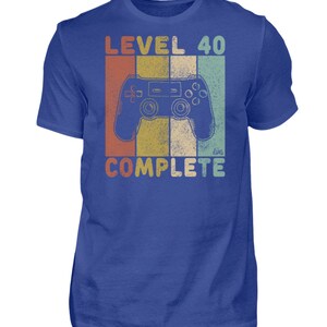 May include: A blue t-shirt with a retro-style graphic of a video game controller and the text "Level 40 Complete".