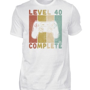 May include: White t-shirt with a retro-style graphic of a video game controller and the text "LEVEL 40 COMPLETE".