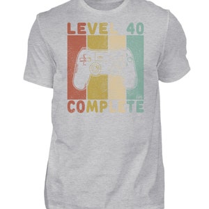 May include: A gray t-shirt with a retro-style graphic that says "Level 40 Complete" and features a video game controller.