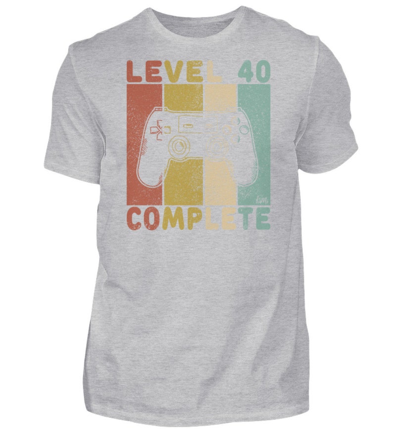 May include: A gray t-shirt with a retro-style graphic that says "Level 40 Complete" and features a video game controller.