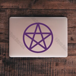 May include: A purple pentacle sticker on a silver laptop. The pentacle is a five-pointed star inside a circle.