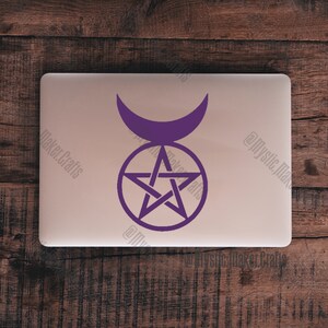 May include: Purple pentagram with a crescent moon symbol above it. The symbol is on a silver laptop.