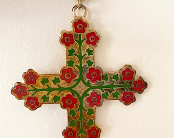 May include: A gold chain necklace with a cross pendant. The cross is decorated with red and green enamel flowers.