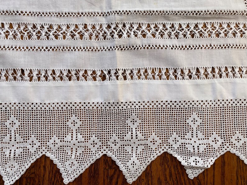 May include: White crocheted lace trim with a scalloped edge. The lace has a delicate pattern and is perfect for adding a touch of elegance to any project.