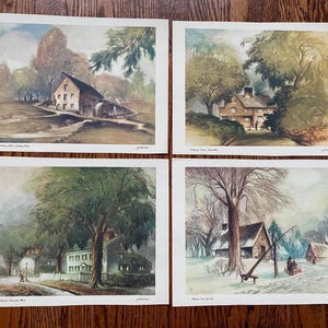 May include: A set of four rectangular landscape prints featuring watercolor-style illustrations of rural scenes. Each print depicts a different house or building surrounded by trees, with small text captions at the bottom of each individual image.