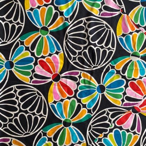 Può includere: Tessuto nero con un motivo ripetuto di fiori colorati e stilizzati e forme circolari bianche. I fiori presentano tonalità vivaci di rosso, arancione, giallo, verde, blu e viola. Il tessuto ha un design grafico audace.