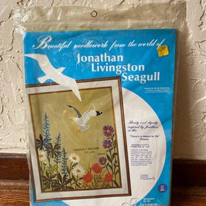 May include: A sealed Paragon Needlecraft kit for a Jonathan Livingston Seagull embroidery project. The packaging features a blue background with a white seagull illustration, floral imagery, and the text There's a reason to life, designed for a 16 inch by 20 inch frame.