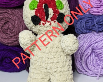 Puede incluir: Un juguete de peluche tejido a crochet con un cuerpo blanco y una cara roja, negra y verde. El juguete está sentado sobre una superficie blanca con ovillos de lana en el fondo. El texto "PATTERN ONLY" está superpuesto en la imagen.