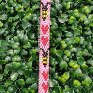 May include: A pink and red pen with a black and yellow bee design. The pen is covered in rhinestones and has the text "Andrea's Custom Crafts" on the side.