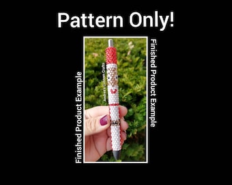 May include: A beaded pen with a Santa Claus design. The pen is white with red and black accents. The beads are small and create a detailed design. The pen is held in a hand.