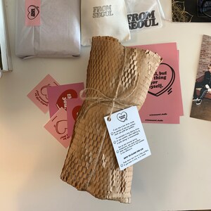 以下が含まれることがあります： ひもで包まれ、ハニカム模様の茶色の紙で固定された茶色の紙の包み。パッケージには、黒い文字が書かれた白いタグが付いています。タグには、「ご注意ください：熱い飲み物を中に入れた場合は、開ける際に熱い表面に注意してください。加湿器は、水を最小限に抑えることで、より長い時間熱いミストで動作するように設計されています。加湿器をより長く動作させるには、製造中に水を補充することをお勧めします。この製品は加湿器専用であり、他の目的で使用しないでください。蒸留水を使用するとより効果的です。」という記載があります。タグには、蓋の閉め方に関する指示も含まれています。