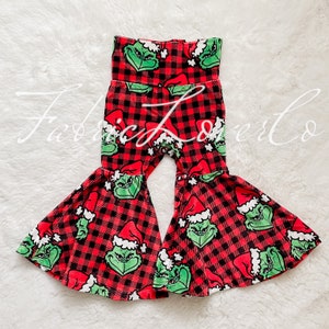 May include: Red and black plaid bell bottom pants with a Grinch print. The pants have a wide waistband and a flared leg.