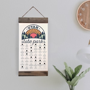 May include: A white and brown printable checklist of Utah state parks. The checklist features a retro-style illustration of a sunset over a forest. The text "UTAH state parks" is printed in blue and orange.