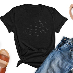 May include: A black t-shirt with a flock of birds graphic and the text "set free" printed on the front.