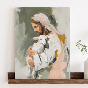 Peut inclure: Peinture abstraite repr&eacute;sentant une figure en robes blanches tenant un agneau. L'&oelig;uvre utilise une palette de couleurs douces, dont le blanc, le p&ecirc;che et l'or, sur un fond vert. La peinture est expos&eacute;e sur une &eacute;tag&egrave;re en bois.