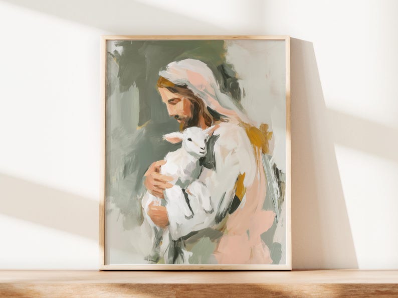 Peut inclure: Une impression d'art encadr&eacute;e repr&eacute;sentant une figure aux longs cheveux bruns et &agrave; la barbe, tenant un agneau blanc. La peinture utilise un style doux et pictural avec des tons sourds de vert, de rose et d'or. L'&oelig;uvre est expos&eacute;e sur une surface en bois.