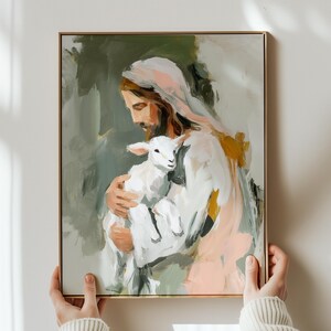 Peut inclure: Une impression d'art repr&eacute;sente une figure aux longs cheveux bruns et une robe blanche tenant un agneau. La peinture a un cadre dor&eacute; et pr&eacute;sente une palette de couleurs douces de blanc, rose, vert et or.