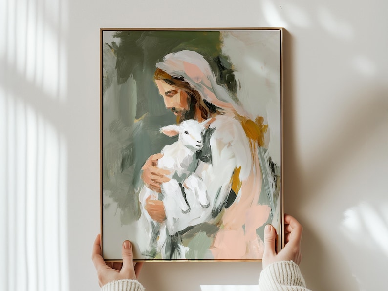 Peut inclure: Une impression d'art repr&eacute;sente une figure aux longs cheveux bruns et une robe blanche tenant un agneau. La peinture a un cadre dor&eacute; et pr&eacute;sente une palette de couleurs douces de blanc, rose, vert et or.