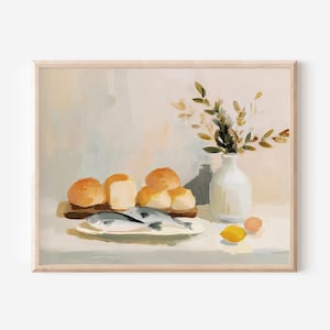 May include: A framed still life painting featuring a rustic arrangement. It depicts a wooden board with bread rolls, a plate with fish, a white vase with foliage, and a lemon. The color palette is soft, with warm tones.