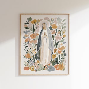 May include: A framed art print featuring a watercolor painting of a religious figure surrounded by colorful flowers. The figure is depicted in a white robe and blue veil, with a halo. The floral arrangement includes shades of orange, yellow, and green.