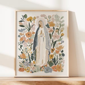May include: Framed art print featuring a watercolor illustration of a religious figure surrounded by colorful flowers. The figure is depicted in a long white robe and a blue veil, with a halo. The floral arrangement includes peach, yellow, and green tones.