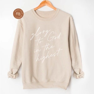 May include: A beige sweatshirt with the text "glory to God in the highest" written in white cursive.