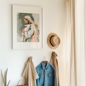 Peut inclure: Une &oelig;uvre encadr&eacute;e repr&eacute;sente une figure tenant un agneau, dans des couleurs douces. Un chapeau de paille et une veste en jean sont accroch&eacute;s au mur. Une &eacute;charpe beige et un sac fourre-tout tiss&eacute; sont &eacute;galement visibles.