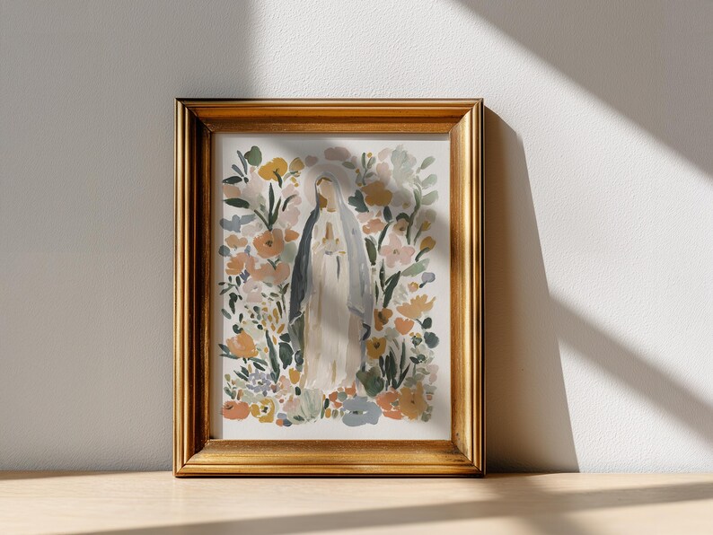 May include: A framed watercolor print featuring a figure in a white robe and veil, surrounded by colorful flowers in shades of yellow, orange, and pink. The artwork is set in a gold-colored frame, creating a classic and elegant aesthetic.