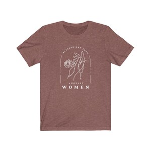 Peut inclure: Un t-shirt marron chin&eacute; avec un motif blanc repr&eacute;sentant une main tenant un chapelet et une rose. Le texte "Blessed are thou amongst women" est imprim&eacute; sous le motif.