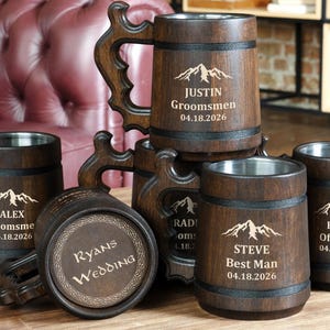 Puede incluir: Un conjunto de jarras de cerveza de madera con interiores de acero inoxidable. Cada jarra está grabada con un nombre, un rol y una fecha, incluyendo "Justin Groomsmen", "Alex Groomsmen", "Steve Best Man" y "Karl Officiant". Una jarra está grabada con "Ryans Wedding".