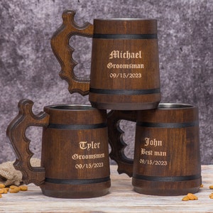 May include: Three wooden beer tankards with decorative handles are stacked. Each tankard has a dark brown finish, a stainless steel interior, and a black band. The tankards are engraved with names, titles, and the date 09/15/2023.