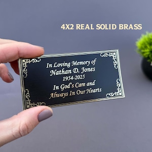 May include: A black brass plaque with gold trim and text that reads "In Loving Memory of Nathan D. Jones 1954-2025 In God's Care and Always In Our Hearts." The plaque is 4x2 inches.