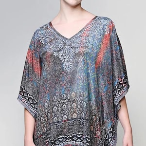 May include: A patterned, V-neck tunic in shades of gray, blue, red, and white. The tunic features an intricate design with geometric and floral elements. The sleeves are short and the hemline has a decorative border.