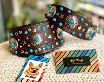 May include: Two brown leather dog collars with turquoise and silver embellishments. The collars are decorated with turquoise stones, silver stars, and silver circular designs. The collars are on a white knitted surface with a tag that says "Pup Bling!" and "By www.BrightSideBedazzled.com".