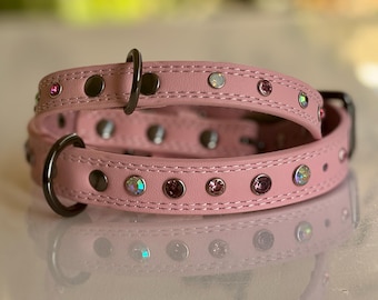 Puede incluir: Un collar de perro de cuero rosa con tachuelas plateadas y diamantes de imitación iridiscentes.
