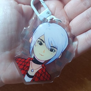 Puede incluir: Un llavero acrílico transparente con un personaje de estilo anime con cabello azul claro y una camisa a cuadros roja. El personaje tiene un collar y un choker negro. El llavero tiene un cierre plateado.