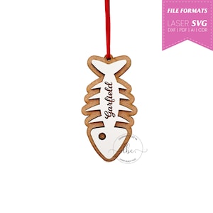 May include: A wooden fishbone-shaped ornament with the name "Garfield" engraved on it. The ornament is white with brown details and has a red string for hanging.