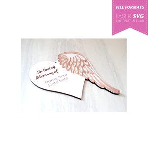 May include: White wooden heart-shaped ornament with a rose gold angel wing attached. The heart has the text "In loving Memory of" and space for a name and date.