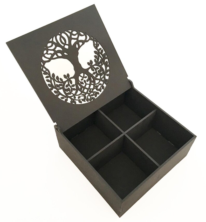 May include: A dark brown wooden box with a hinged lid. The lid has a cutout design of a tree of life. The box has four compartments inside.