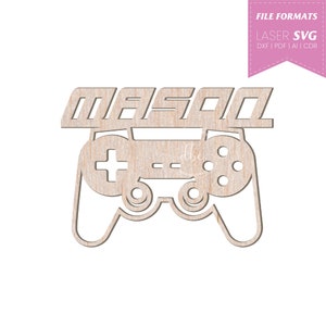 Puede incluir: Un recorte de madera de un mando de videojuego con el nombre "MASON" encima.