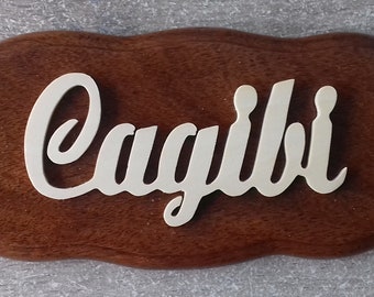 May include: A wooden sign with the name "Cagili" written in white cursive lettering.